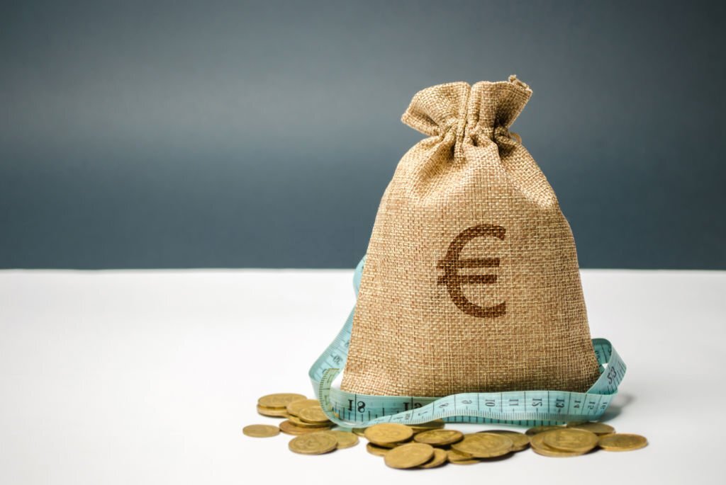bolsa de yute con euros de las subvenciones para pymes sobre monedas y billetes