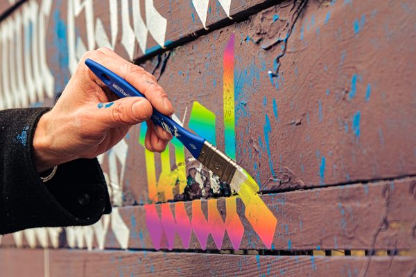 comunicación inclusiva en las empresas, mano pintando caligrafía que se vuelve color arcoiris